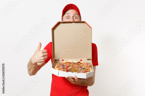 Delivery smiling man in red uniform isolated on white background. Male pizzaman in cap, t-shirt working as courier or dealer holding italian pizza in cardboard flatbox. Copy space for advertisement.