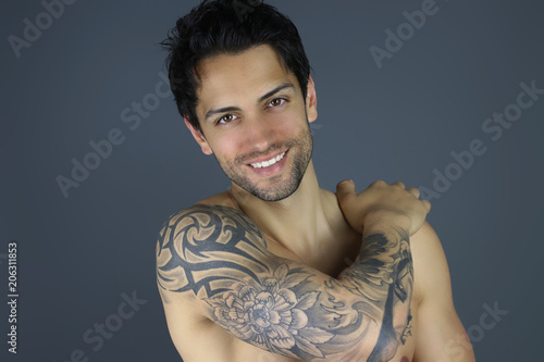 bel homme tatoué posant devant un fond gris photo