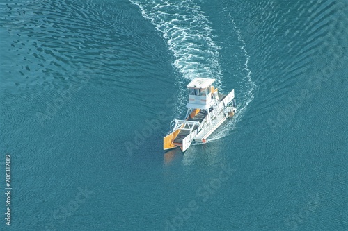 Anti pollution boat working on a coast line  in Dubai and collecting all floating objects. Ocean cleaning, plastic collection.