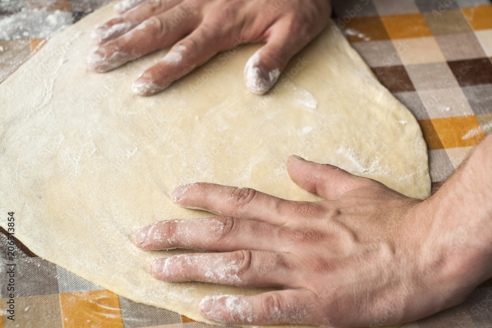 Cooking and home concept - close up of male hands kneading dough on a background in cell Cooking and home concept - close up of male hands kneading dough on a background in cell