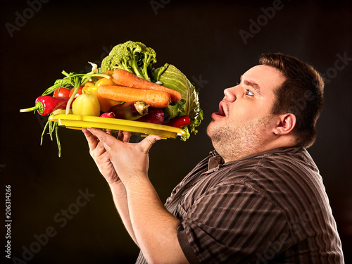 Diet fat man eating healthy food with vegetables for overweight male. Hungry person ready to eat everything. Vegetables for diet in unlimited quantities. Dietary breakfast for weight loss.