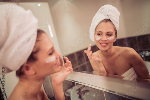 Beautiful woman applying cream on her face