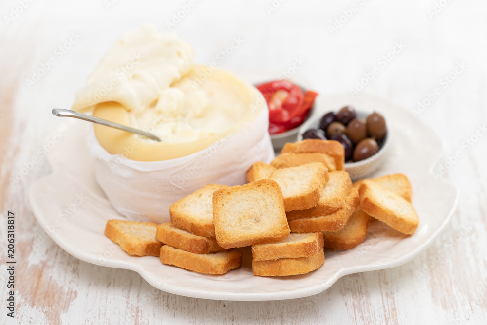 toasts with cheese, olives and red pepper on white dish toasts with cheese, olives and red pepper on white dish