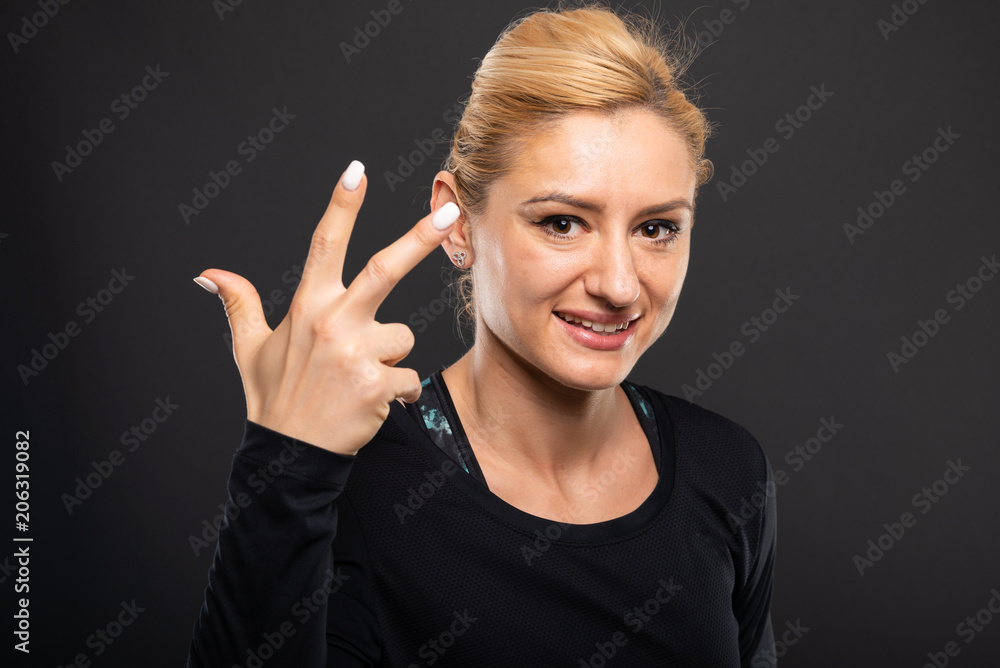 Portrait of pretty gym female trainer showing number three. Portrait of pretty gym female trainer showing number three.