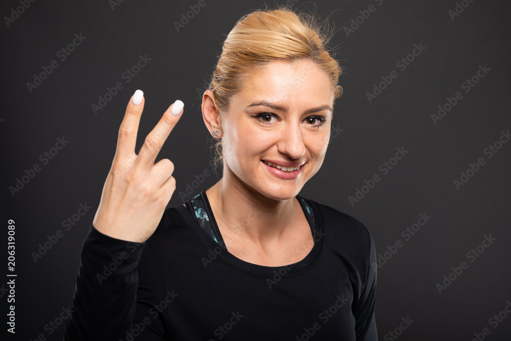 Portrait of pretty gym female trainer showing number two. Portrait of pretty gym female trainer showing number two.