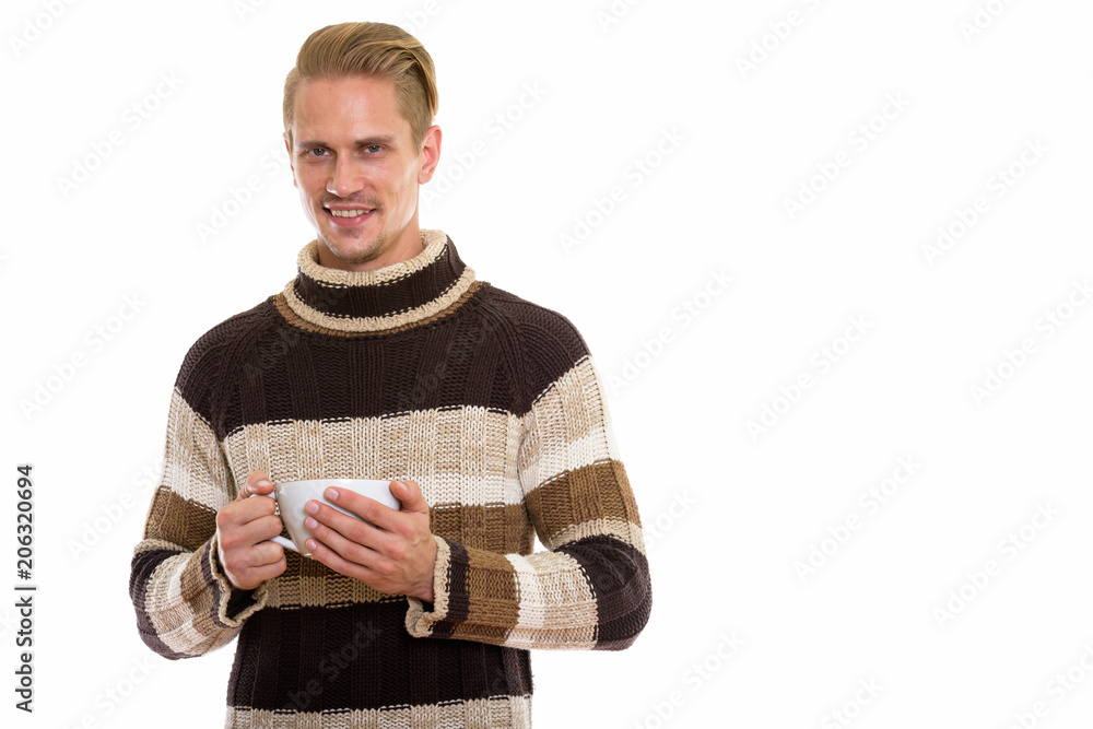 Studio shot of happy young handsome man smiling while holding co