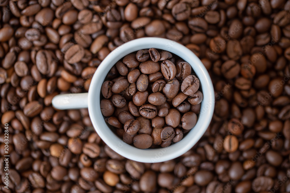 Kaffee-Bohnen in einer weissen Tasse auf braunem Kaffee-Bohnen Hintergrund Kaffee-Bohnen in einer weissen Tasse auf braunem Kaffee-Bohnen Hintergrund