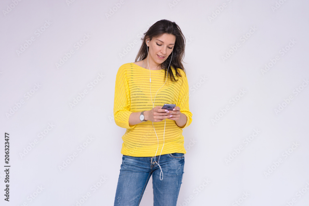Portrait of a beautiful brunette girl on a white background typing on a smartphone in hands. Portrait of a beautiful brunette girl on a white background typing on a smartphone in hands.