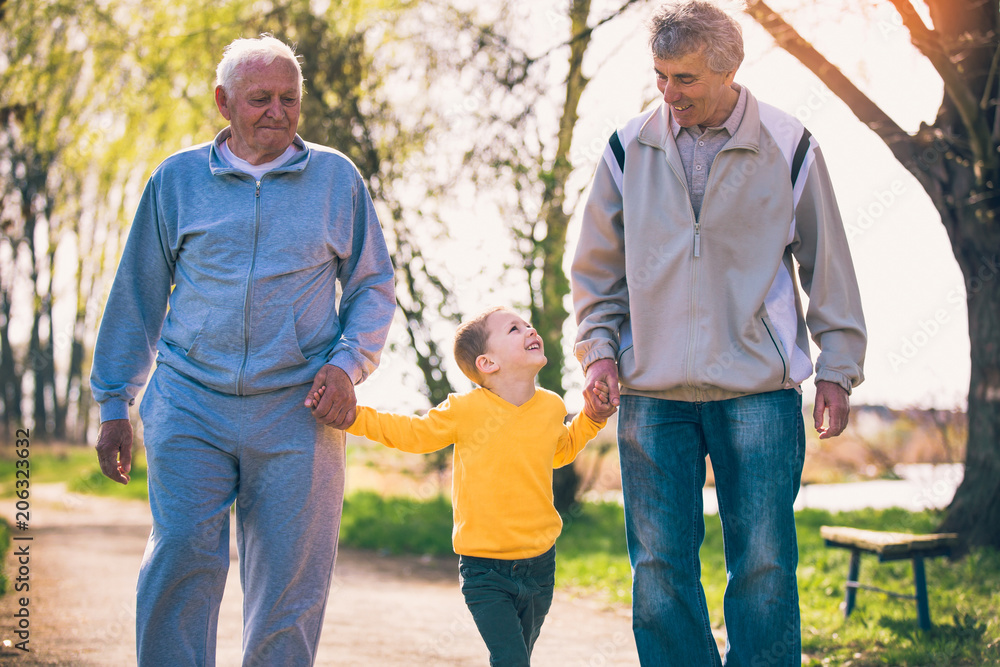 Two grandfather walking with the grandson in the park Two grandfather walking with the grandson in the park
