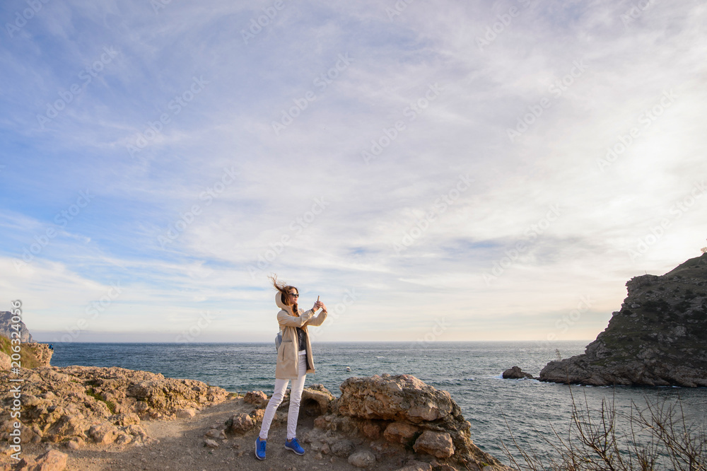 Beautiful girl outdoors. Spring day. The girl with long hair photographes itself near the sea