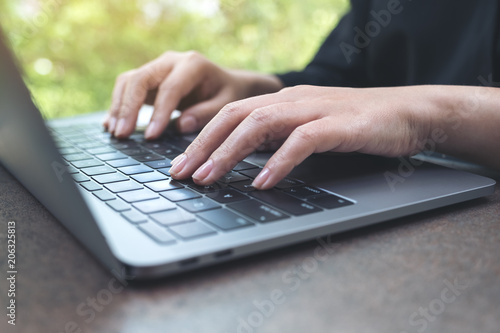 Closeup image of hands working and typing on laptop keyboard in office