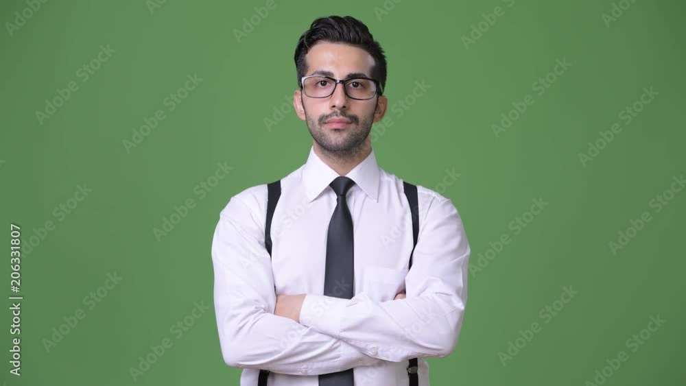 Young handsome bearded Persian businessman against green background Young handsome bearded Persian businessman against green background