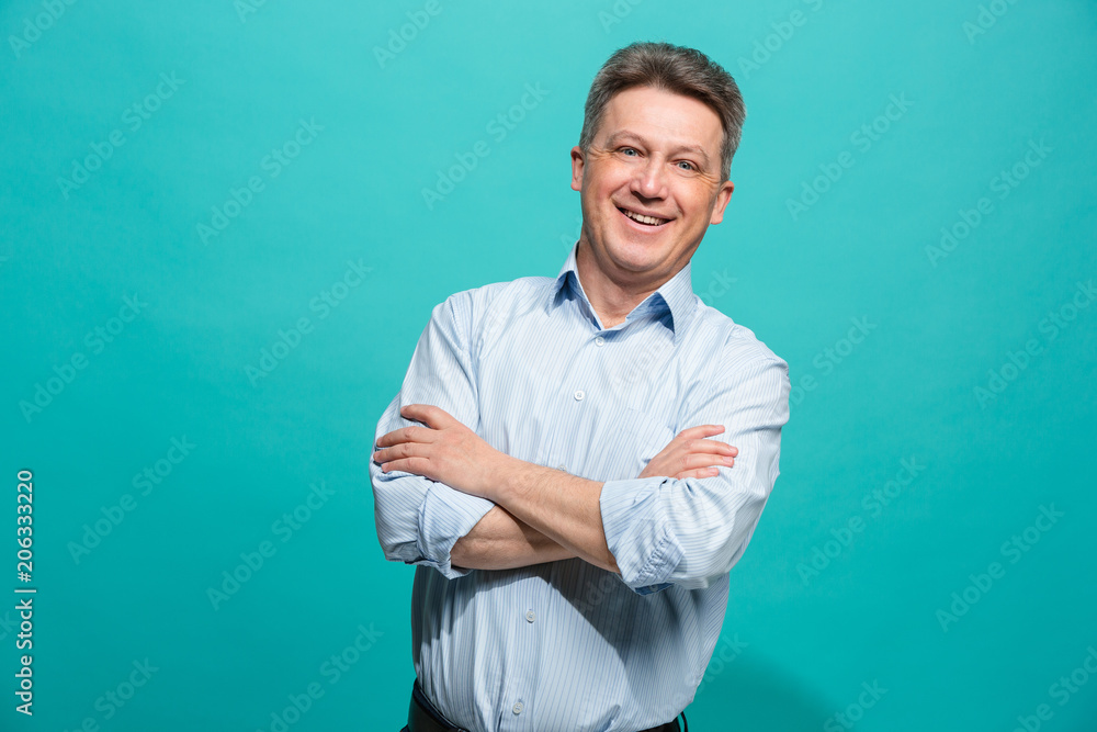The happy businessman standing and smiling against blue background. The happy businessman standing and smiling against blue background.