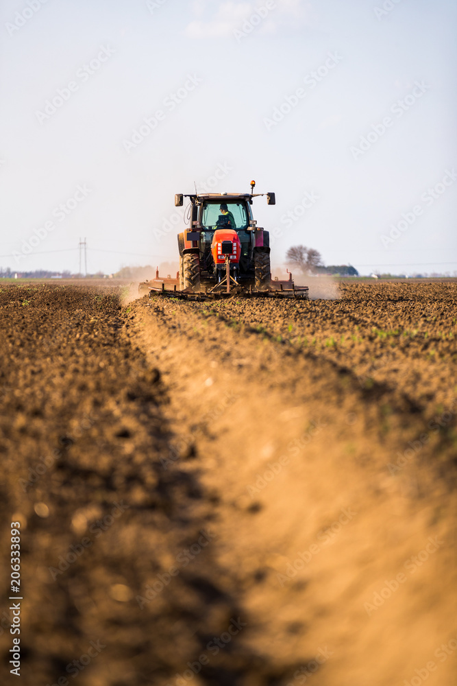 Fototapeta premium Farmer in tractor preparing land with seedbed cultivator as part of pre seeding activities in early spring season of agricultural works at farmlands.