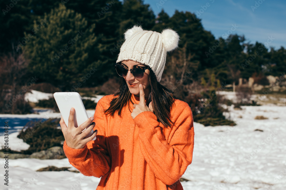 Young and cheerful woman using her tablet, to stay connected with her family, on the mountain a day of snow and sun. Lifestyle. Young and cheerful woman using her tablet, to stay connected with her family, on the mountain a day of snow and sun. Lifestyle.
