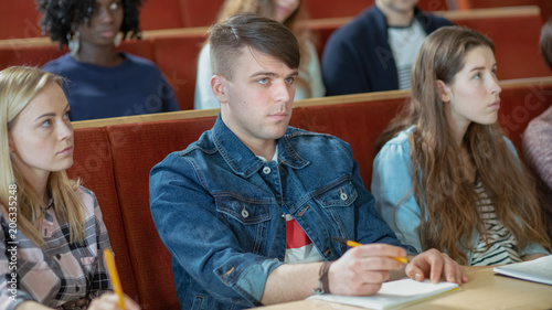 Beautiful and Intelligent Young Caucasian Man Listens to a Lecture in a Classroom Full of Multi Ethnic Students.