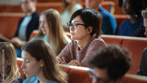 Asian Young Man Among His Fellow Students in the Classroom. Young Bright People Listening to a Lecture and Take Notes while Studying at the University.