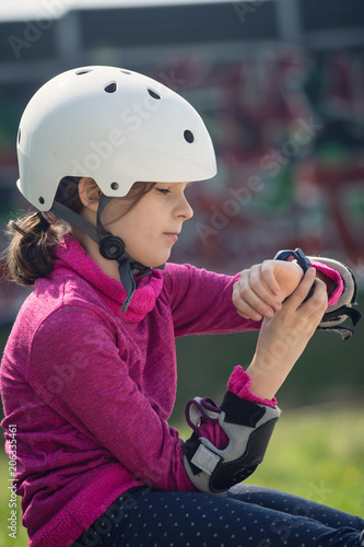Close-up of skateboarder girl checking message on smartwatch.