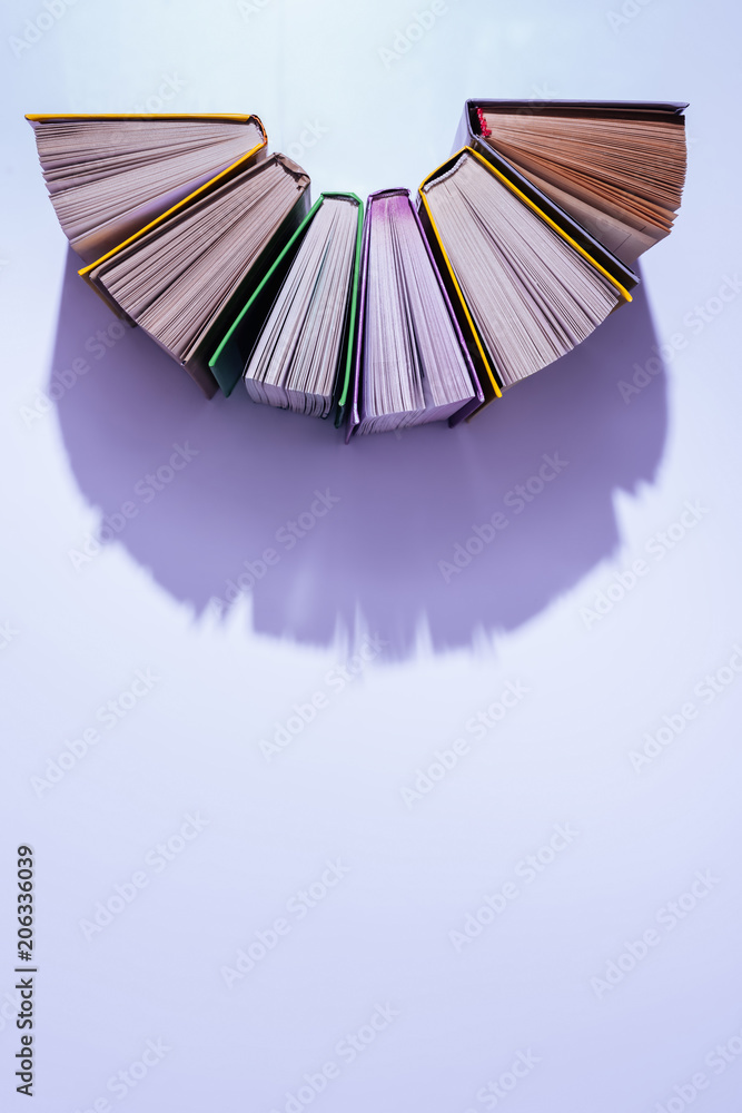 top view of stack of books in half circle on violet table