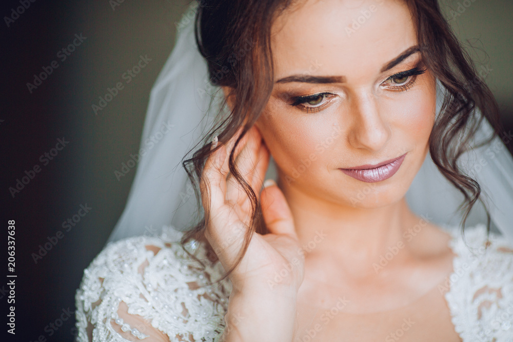 The bride in a white dress wears gold earrings with pearls. In the hands of the bride decoration in the form of a earring. Wedding Morning. Jewelry. Close-up makeup. The bride in a white dress wears gold earrings with pearls. In the hands of the bride decoration in the form of a earring. Wedding Morning. Jewelry. Close-up makeup.
