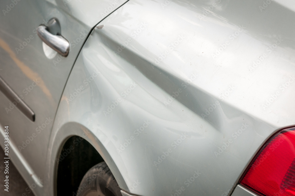Rear side of broken and damaged silver car wreck in crash accident with scratched paint in collision close up Rear side of broken and damaged silver car wreck in crash accident with scratched paint in collision close up