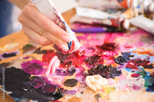 Closeup of paintbrush in woman hands mixing paints on palette