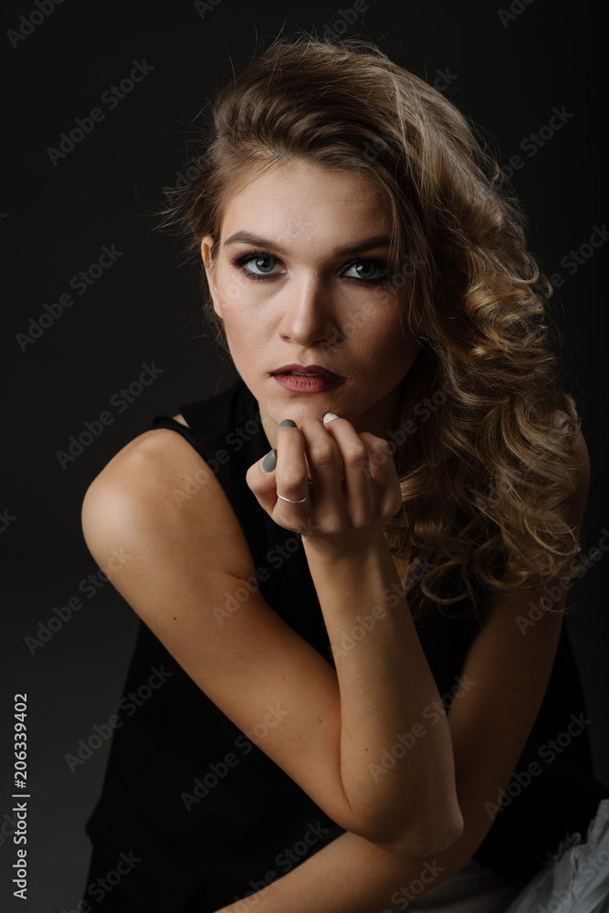 Close up portrait of attractive blonde woman with beautiful make up wearing black blouse posing isolated against black background in the studio Close up portrait of attractive blonde woman with beautiful make up wearing black blouse posing isolated against black background in the studio