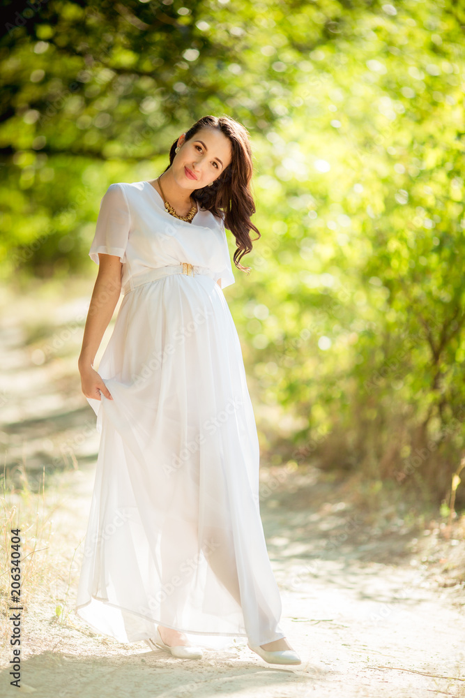 Beautiful pregnant woman with her husband in green garden