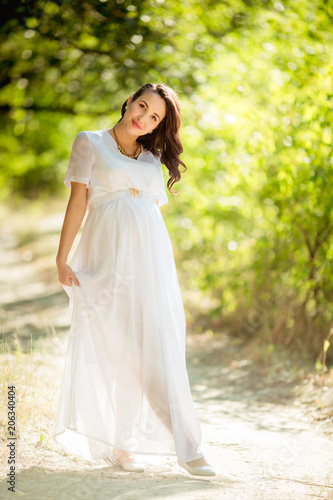 Beautiful pregnant woman with her husband in green garden