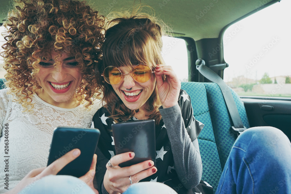 custom made wallpaper toronto digitalDos amigas usando sus teléfonos móviles mientras hacen un viaje en coche 