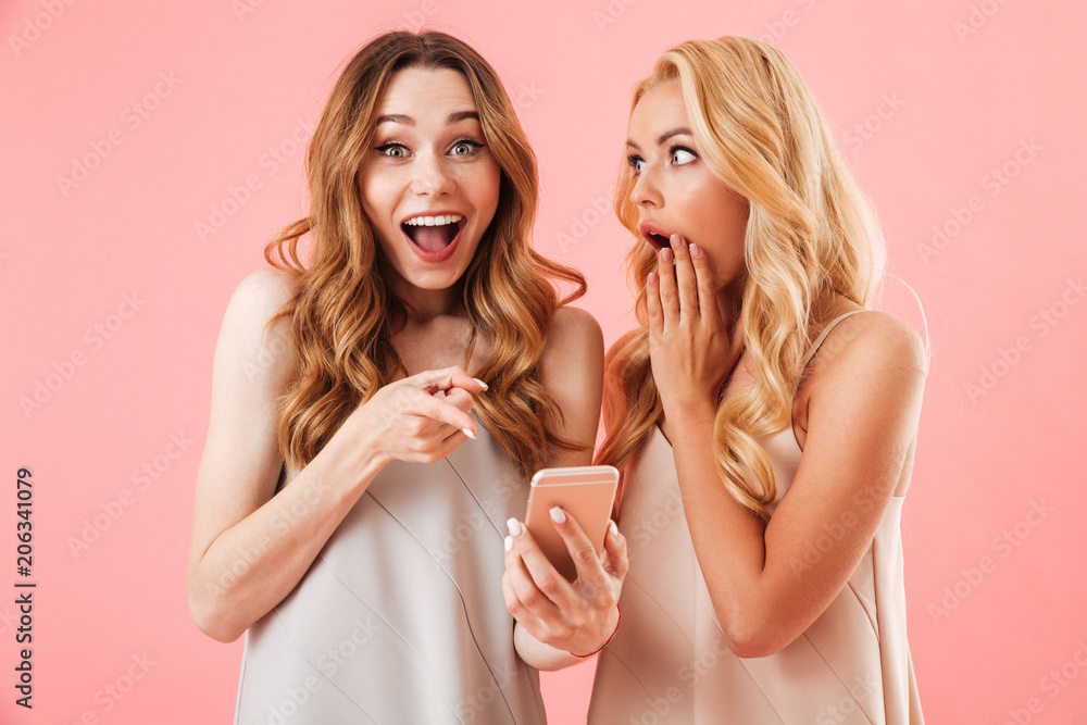 Two shocked pretty women in pajamas using smartphone together Two shocked pretty women in pajamas using smartphone together