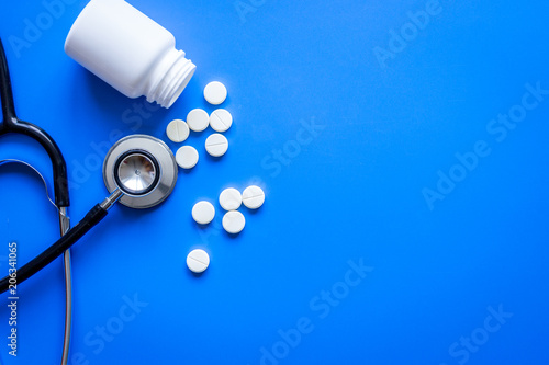 stethoscope and meds on doctors workplace on blue background top photo