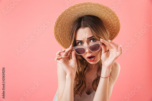 Surprised displeased brunette woman wearing in dress and hat