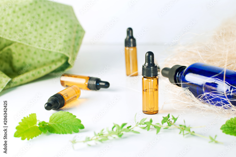 Brown and blue bottles of essential oil with fresh mint and thyme Brown and blue bottles of essential oil with fresh mint and thyme