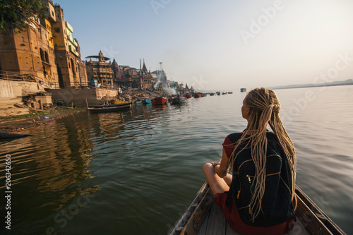 Woman traveler on a boat glides through the water on the Ganges river of Varanasi, India.
