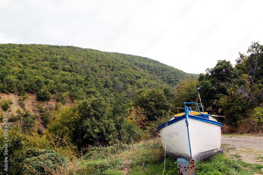 old boat lies near the road against the background of hilly area old boat lies near the road against the background of hilly area
