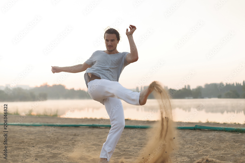 Athletic capoeira performer workout training on the beach sunris Athletic capoeira performer workout training on the beach sunris