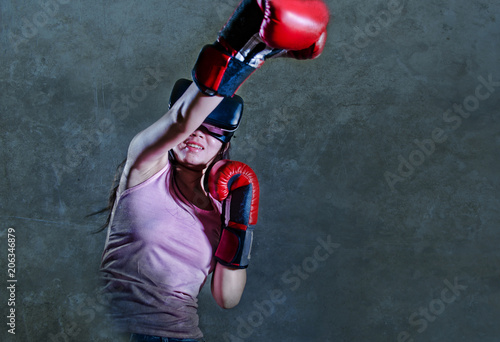 portrait of young woman with boxing gloves playing video game using VR virtual reality goggles simulating boxer fighting 3D illusion combat