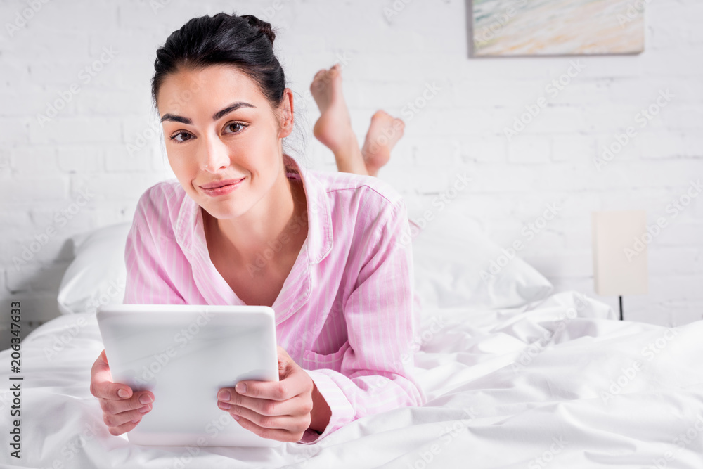 portrait of smiling woman in pajamas with tablet while lying on bed at home portrait of smiling woman in pajamas with tablet while lying on bed at home