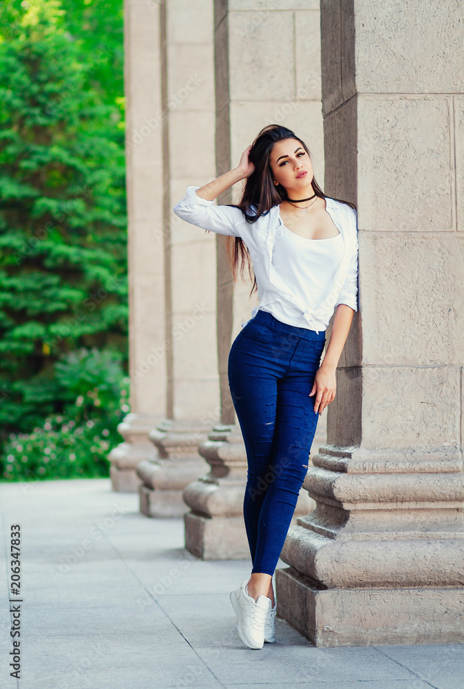 young sexy stylish girl, slim tall girl in jeans and shirt on the street