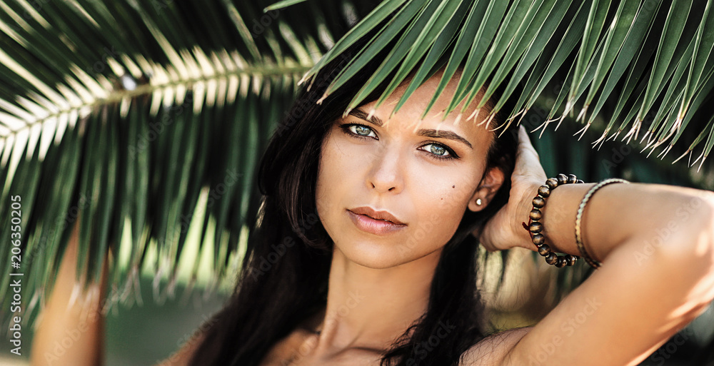Portrait of a beautiful woman in palm leaves