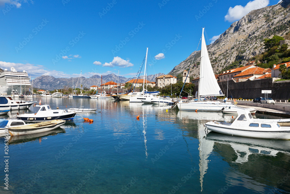 Montenegro. A beautiful view of the marina with boats, yachts and a cruise ship in the port of the old town of Kotor with ancient stone walls