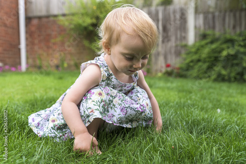 Little girl in a flowery dress playing in the garden