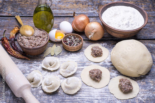 Homemade dumplings of their dough and minced meat on a wooden board, background.