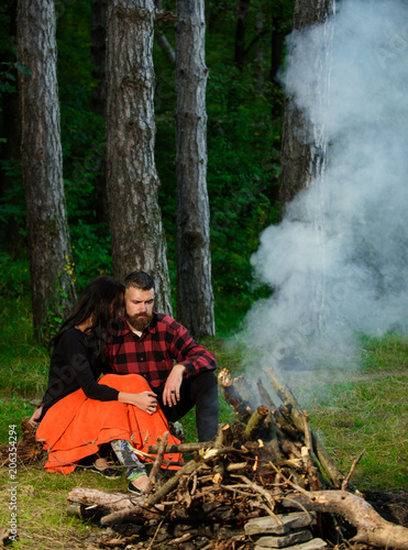 Couple in love at picnic with fire in forest,