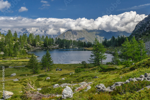 Arpy Lake, Valle d’Aosta, Italy. Alpine pond on Italian alps. Beautiful mountain panorama. Enjoying nature in summer day with blue cloudy sky. Landscape from Colle San Carlo, La Thuile, IT. 