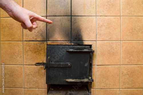 Foto Man's hand pointing to the black soot marks from furnace on tiles wall