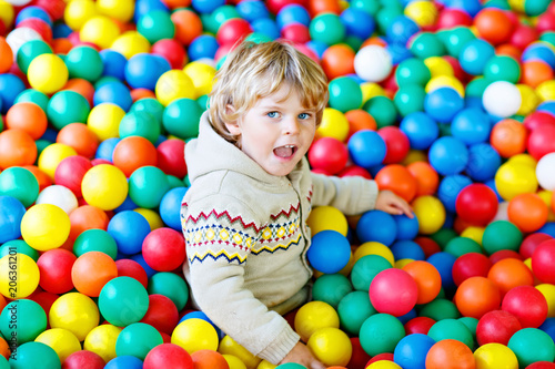Little kid boy playing at colorful plastic balls playground