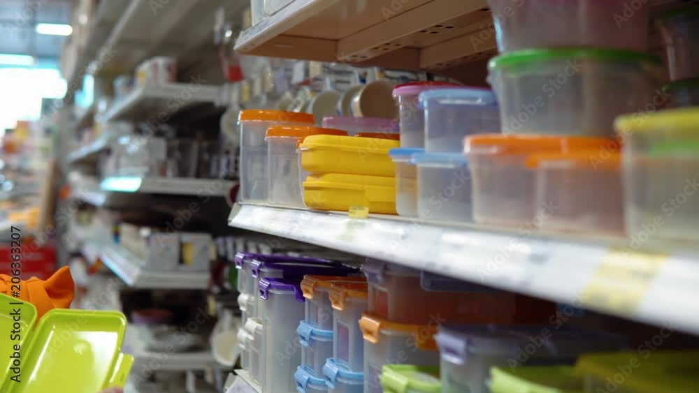 Mom and daughter together chooses a plastic food container in the department with utensils in the supermarket. Mom and daughter together chooses a plastic food container in the department with utensils in the supermarket.