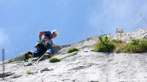 mountain guide climbing a steep slab pitch of a hard rock climbing route in the Alps of Switzerland